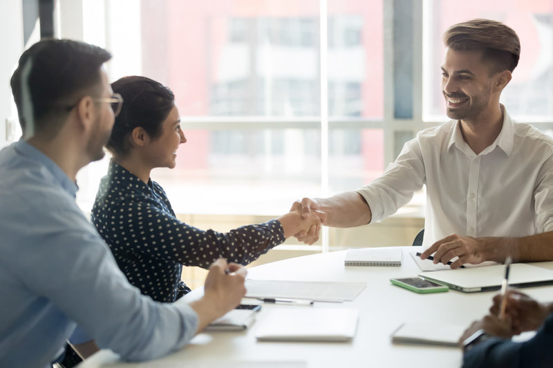 Smiling diverse partners handshake collaborating at office meeting